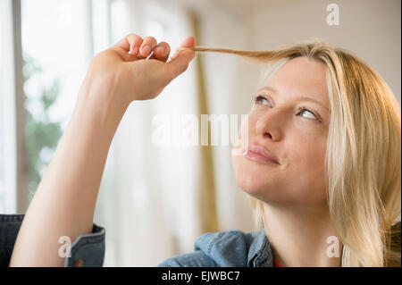 Donna torcendo i suoi capelli Foto Stock