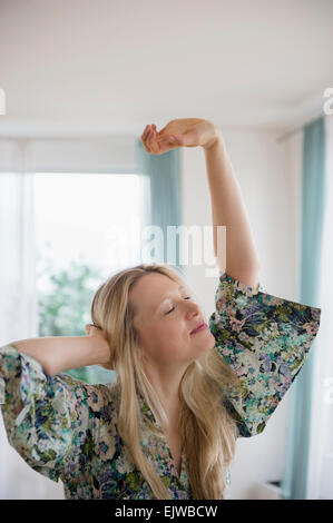 Donna bionda stretching a casa Foto Stock