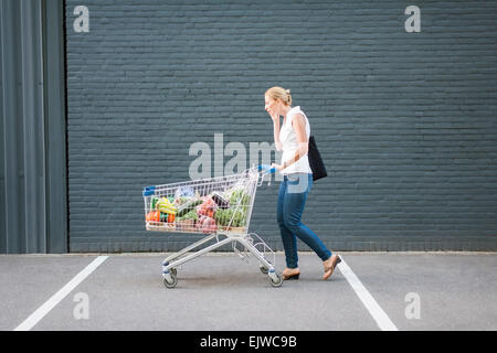 Donna che cammina con carrello Foto Stock