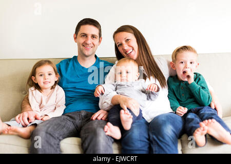 Ritratto di famiglia con tre bambini (2-3, 4-5) seduto sul divano Foto Stock
