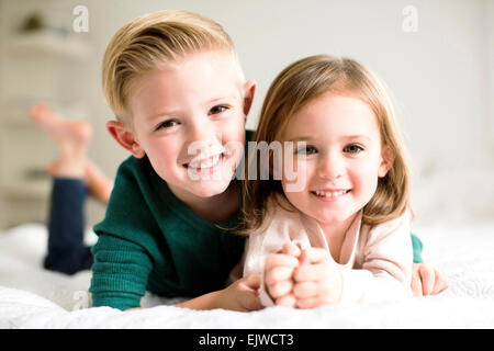 Ritratto di fratelli (2-3, 4-5) giacente sul letto Foto Stock