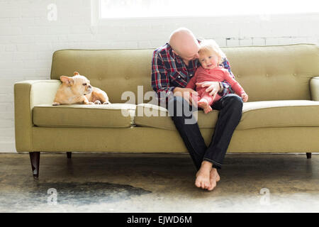 Padre seduto sul divano abbracciando baby figlio (2-3) Foto Stock