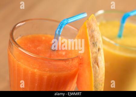 Freschi succhi di papaia guarnito con una fetta di papaia, succo di mango in retro (messa a fuoco selettiva) Foto Stock