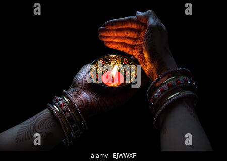 Donna mani con henna holding candela isolata su sfondo nero con tracciato di ritaglio Foto Stock