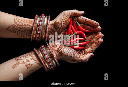 Donna mani con henna holding peperoncino rosso isolato su sfondo nero con tracciato di ritaglio Foto Stock