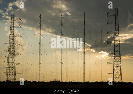 Array di comunicazione radio antenne su sfondo con cielo nuvoloso, al tramonto Foto Stock