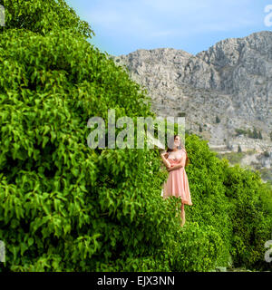 La donna in piedi di piante verdi sulle montagne Foto Stock