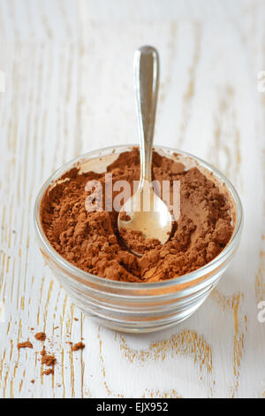 Cacao in polvere con un cucchiaio su una tavola di legno Foto Stock