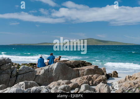 Onde si infrangono in vista pabbay con scuotipaglia / tourist rilassante con border terrier Foto Stock