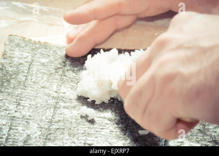 Porre il riso su nori per la preparazione di sushi Foto Stock