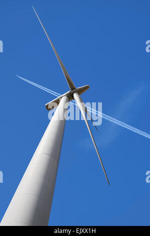Turbina eolica e Aereo Sentiero di vapore contro un cielo blu, UK. Angolo basso. Foto Stock