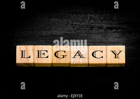 Parola Legacy. Legno cubetti di piccole dimensioni con lettere isolati su sfondo nero.Concetto di immagine. Foto Stock