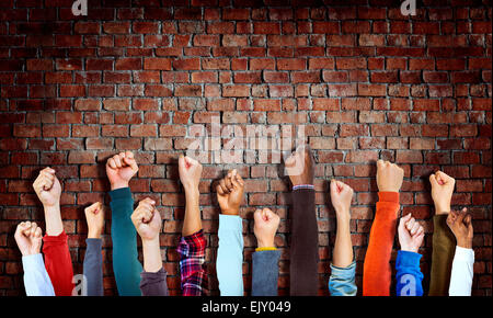 Gruppo di diverse mani sollevate su un muro di mattoni Foto Stock