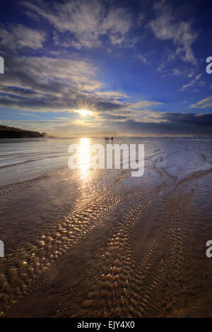 Surfisti sulla Polzeath Beach, catturato poco prima del tramonto. Foto Stock