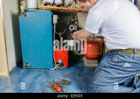 L'uomo le riparazioni centrale di una caldaia di riscaldamento Foto Stock