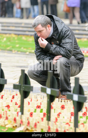 L'uomo legge i messaggi su croci di legno con papaveri prevista per il Giorno del Ricordo. Foto Stock