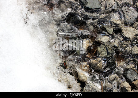 Dettaglio fotografia di ghiaccio in fusione sulle rocce in un inverno in Ontario, Canada Foto Stock