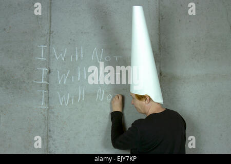 Donna che indossa un cappello dunce iscritto non mi su un muro di cemento Foto Stock