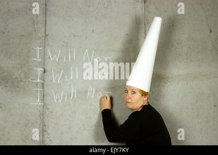 Donna che indossa un cappello dunce iscritto non mi su un muro di cemento Foto Stock