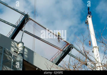 Workman fissaggio rete di sicurezza sul tetto dell'Etihad Stadium, South Stand progetto di espansione, Manchester, Inghilterra, Regno Unito Foto Stock