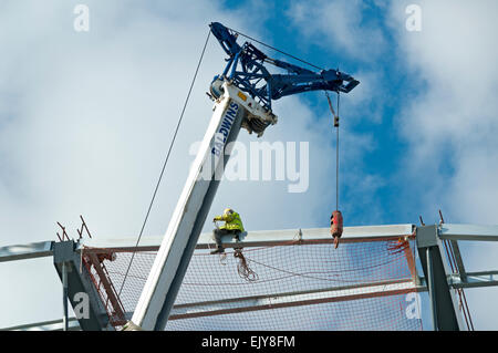 Workman fissaggio rete di sicurezza sul tetto dell'Etihad Stadium, South Stand progetto di espansione, Manchester, Inghilterra, Regno Unito Foto Stock