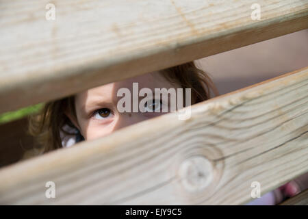 Il bambino guarda attraverso il crack assi di legno Foto Stock