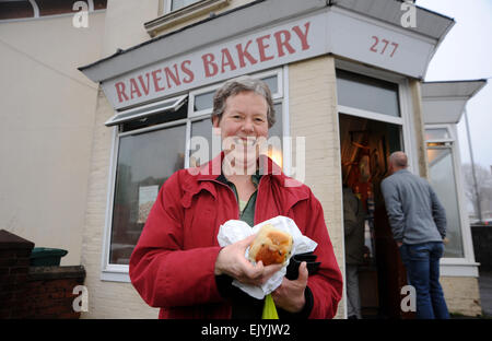 Brighton Regno Unito 3 Aprile 2015 - Il cliente dopo aver acquistato la sua croce calda panini da corvi Bakery in Brighton questa mattina per battere la tradizionale corsa. Il piccolo fornai nell'area Fiveways di Brighton è diventato famoso nella zona e che si aspettano di fare e vendere ciambelle 5000 oggi per le vacanze di Pasqua fotografia scattata da Simon Dack/Alamy Live News Foto Stock