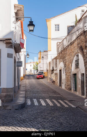 Strada stretta di Evora con il restante di un acquedotto romano in Portogallo Foto Stock