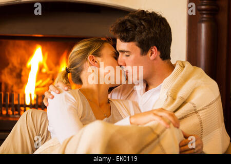 Intimo coppia giovane kissing a casa davanti al camino Foto Stock