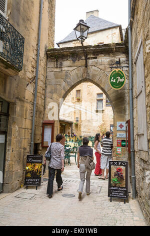 I turisti a piedi attraverso un arco in ciottoli strette strade medievali di Sarlat Dordogne. Foto Stock