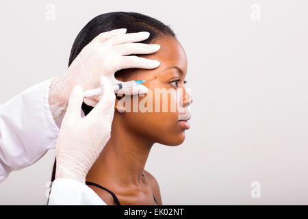 Giovane donna africana la ricezione di chirurgia plastica di iniezione sul suo viso Foto Stock