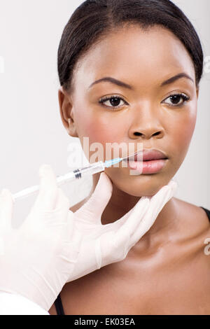 Bella Afro American donna cosmetico ricevente iniezione nella sua labbra Foto Stock