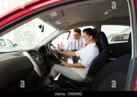 Auto consulente di vendita che mostra una nuova vettura al potenziale cliente in showroom Foto Stock