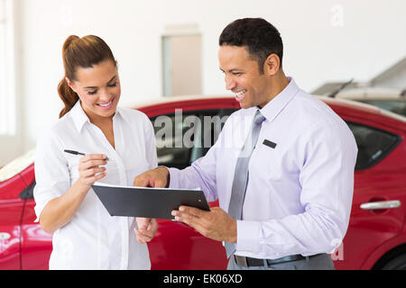 Donna felice di acquistare una nuova auto presso lo showroom del veicolo Foto Stock