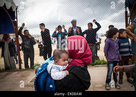 (150403) -- KOBANE (Siria), 3 aprile 2015 (Xinhua) -- Un siriano rifugiato curdo e il suo bambino arrivano in Kobane, Siria, 3 aprile 2015. Alcuni rifugiati siriani che erano fuggiti in Turchia tornò a Kobane dopo combattenti curdi sloggiato Stato islamico (SI) militanti dalla città. (Xinhua/Ahmad Halabisaz) Foto Stock