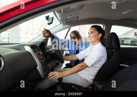 Felice venditore spiegando funzionalità di auto per giovani femmine cliente Foto Stock