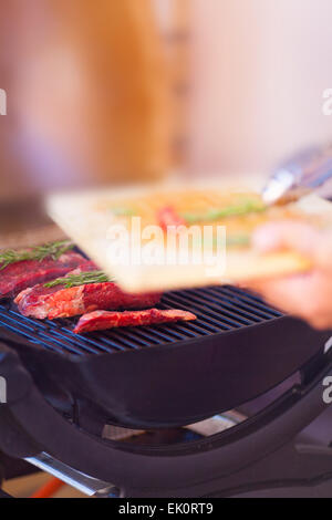 Man mano con carne fresca preparazione sul grill vicino fino Foto Stock