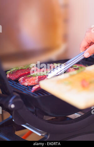 Man mano con carne fresca preparazione sul grill vicino fino Foto Stock