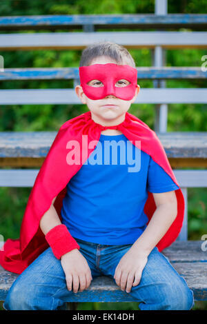 Ragazzo vestito in capo e la maschera seduta sullo sport tribune Foto Stock