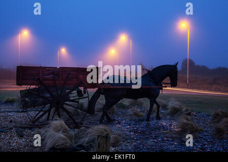 Meteo nebbioso a Southport, Merseyside, Regno Unito settembre 2015. Meteo nel Regno Unito. Tramonto colorato sul Mare d'Irlanda e replica di un carro di gamberi trainato da cavalli, o carrozza, originariamente utilizzato dai pescatori locali, che ora si trova sulla rotonda di Weld Road, adiacente alla riva. Carri trainati da cavalli o veicoli meccanici utilizzati per reti da traino dietro di essi, un metodo di pesca noto come «shanking». Foto Stock