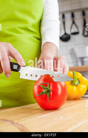 Donna con le mani in mano il taglio di pomodoro fresco su cucina Foto Stock