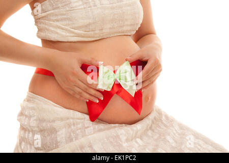 Ventre della donna incinta con un nastro rosso e verde di prua Foto Stock