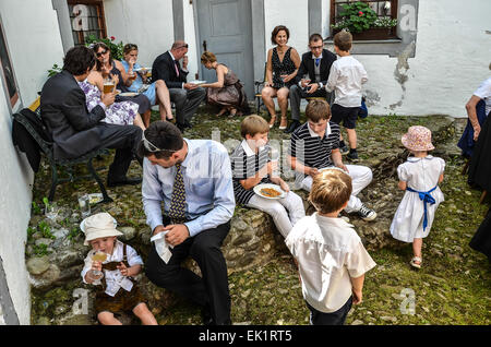 Dopo il matrimonio cerimonia party all'aperto agli ospiti di nozze abiti da sposa cappelli colorati mangiare bere parlando alle famiglie dei bambini Foto Stock