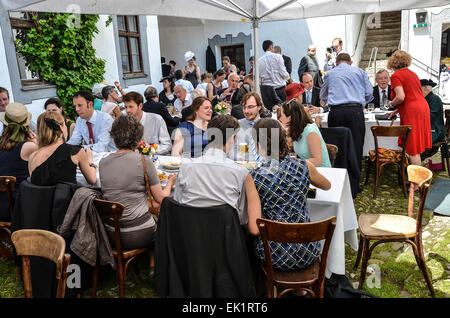 Dopo il matrimonio cerimonia party all'aperto agli ospiti di nozze abiti da sposa colorati fantasia cappelli Cappelli mangiare bere parlando Foto Stock