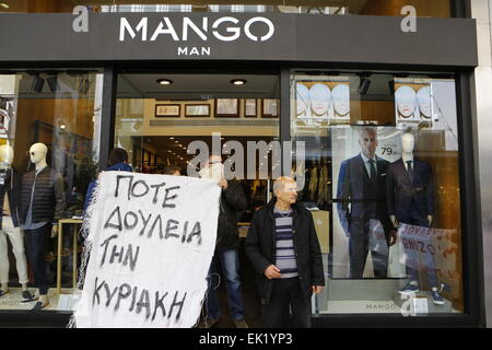 Atene, Grecia. 5 aprile 2015. Manifestanti tenere premuto su un banner al di fuori di un negozio di Mango, che recita "Mai lavorare di domenica". Retail i lavoratori hanno protestato in Atene Ermou Street contro l'apertura di negozi di domenica in Grecia. Il nuovo governo ha annunciato la sua intenzione di modificare la legge che attualmente consente ai negozi di aprire il 7 domeniche dell'anno, ma non hanno agito su questo ancora. Credito: Michael Debets/Alamy Live News Foto Stock