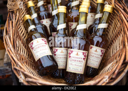 Bottiglie di Calvados per la vendita in cesto presso il negozio in Honfleur, in Normandia, Francia, Europa Foto Stock