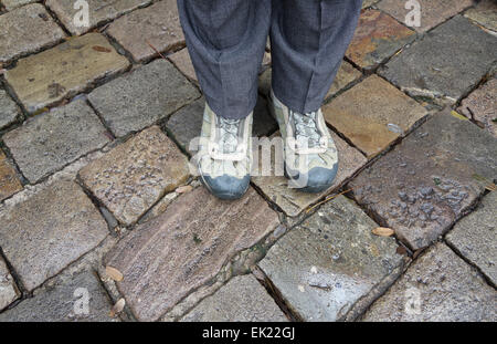 Piedi in scarponi in piedi su pietre ciottoli in giornata piovosa a Barcellona Foto Stock