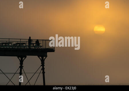 Aberystwyth, Wales, Regno Unito. 5 Aprile, 2015. Regno Unito: meteo alla fine di una Domenica di Pasqua di inviolata il caldo sole primaverile, il sole tramonta moodily in banchi di rullatura di foschia marina su Cardigan Bay a Aberystwyth sulla West Wales coast, UK. Il clima caldo è previsto che rimanga per i prossimi giorni, specialmente nella parte occidentale del Regno Unito, con temperature che raggiungono i 15ºC / 60ºF Photo credit: keith morris / Alamy Live News Foto Stock