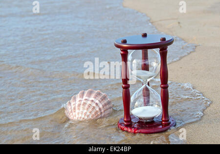 Seashell con timer di sabbia su una spiaggia. Foto Stock