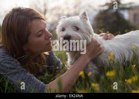 Donna felice gioca con il suo cane, un Westie (West Highland Terrier). Foto Stock